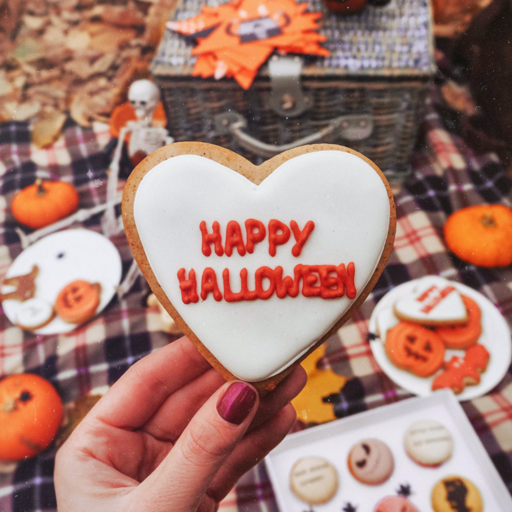 a photo of a hand holding halloween cookie at a picnic in an autumn forrest 