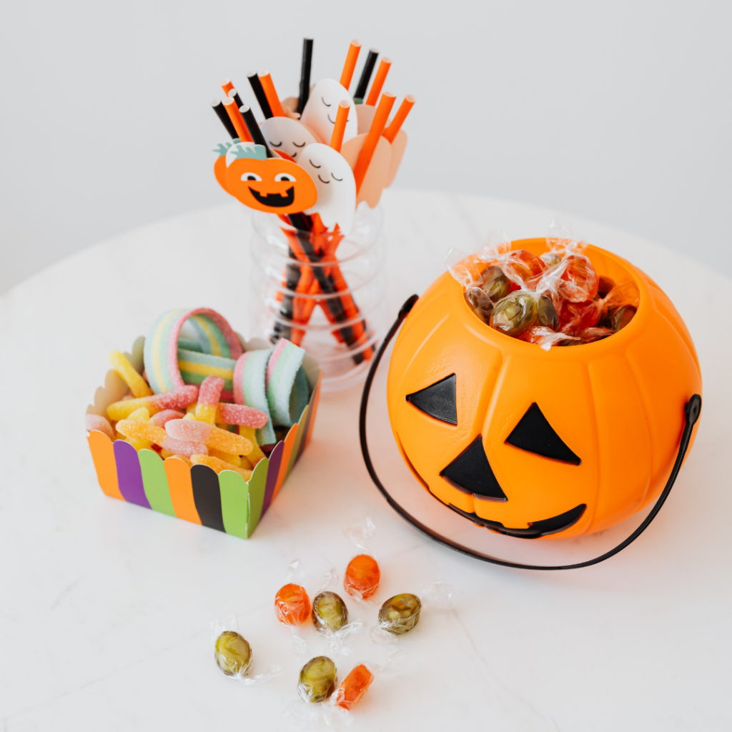 Photo of halloween, sweets, straws and a pumpkin on a table